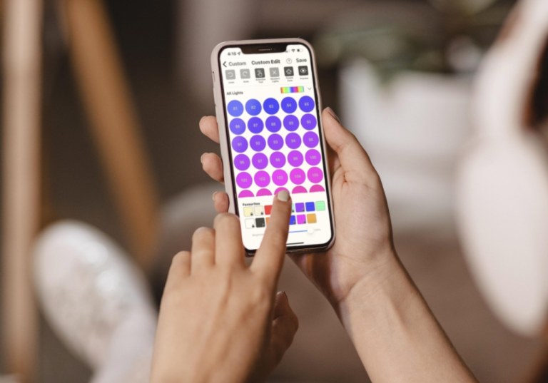 Close up of hands holding a smart phone with an app open that controls LED lights.