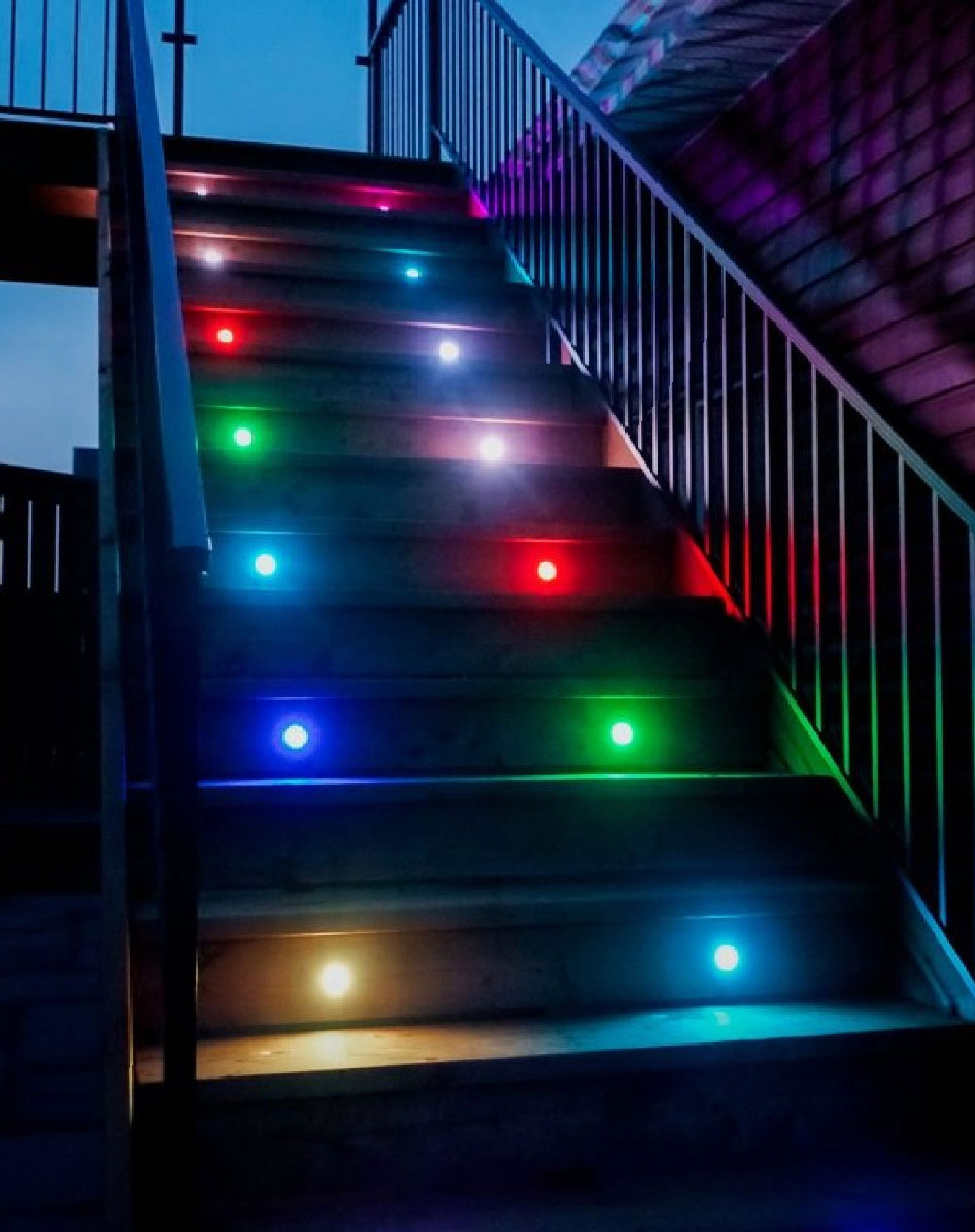 Deck stairs with 2 lights per tread illuminated in a combination of red, green, yellow and blue.